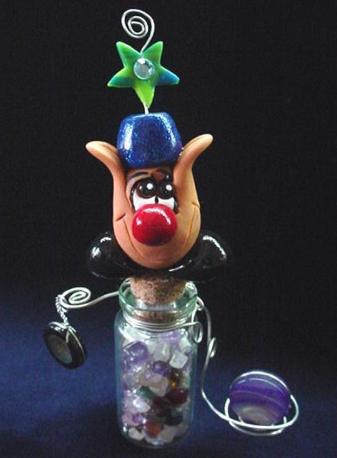 Handmade with Fimo. Glass bottle full of polished Quartz pieces. Two polished rocks are resting in silver wire. Austrian crystal is used for final details. 