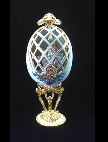  Painted in light blue satin color with enamel gold details. Accentuated w/AB, Sapphire Austrian Crystals and decorated with porcelain blue, purple and pink roses. Medium Drop shape Austrian Crystals embellish the front door. Decorated box available for this eggypiece.