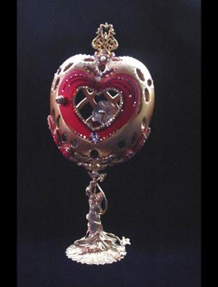 Front red heart door opens. Inside, one large drop AB Austrian Crystal and red heart shaped crystal, both resting on a red velvet pillow with gold color details. This piece was imperial gold color and red satin finish. Accented with AB Austrian Crystals and red Ruby crystals. 18K gold plated stand and findings. Decorated box available for this eggypiece. 