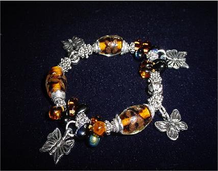 Handcrafted Jewelry Blue & Golden Glass Beads Bracelet -  Handcrafted with Translucent Dk. Blue and Amber Yellow Drop Glass beads. Transparent Lampwork Golden large glass beads are used for a floral and romantic look. Embellished with Silver plated  beads, charms and findings. Stretch cord is used for flexibility  Beautiful and Elegant!