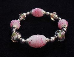 Handcrafted Jewelry Pink Glass Beads Bracelet - Handcrafted with Pink and White Large oval and medium round Glass beads. Transparent Lampwork pink roses flower glass beads are used for a floral and romantic look. Embellished with Silver plated beads and findings. Stretch cord is used for bracelet band. Beautiful and Elegant!
