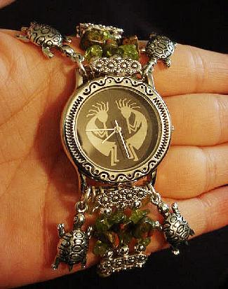 Handcrafted Semi-precious Kokopelli Watch 1 - Handcrafted with Semi-precious Unachite and Peridot Stones. Embellished with Silver plated beads and findings. Five turtle charms are used for final details. Stretch cord is used for watch bands. Round Large Silver watch face. Two Kokopelli's designs enhance the watch sphere. Quartz function and mechanical system. Stainless Steel back. Beautiful, Elegant and Southern look.