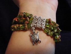 Handcrafted Semi-precious Kokopelli Watch 1- Handcrafted with Semi-precious Unachite and Peridot Stones. Embellished with Silver plated beads and findings. Five turtle charms are used for final details. Stretch cord is used for watch bands. Round Large Silver watch face. Two Kokopelli's designs enhance the watch sphere. Quartz function and mechanical system. Stainless Steel back. Beautiful, Elegant and Southern look.